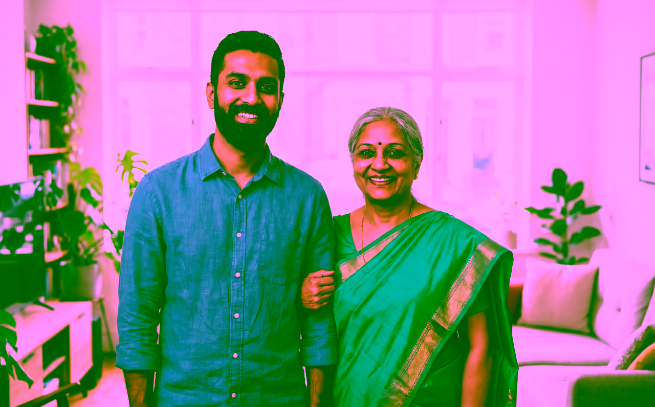 Indian mother in a teal saree at home with the adult son who sponsored her visa